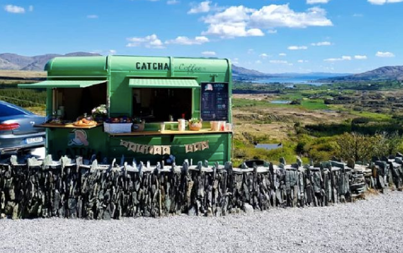 green coffee trailer with blue skies and countryside views in the background