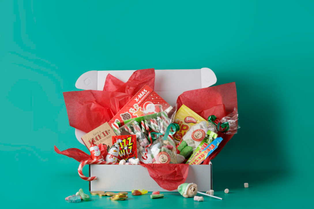 a box full of old fashioned sweets, treats and candy canes, with a red ribbon around it