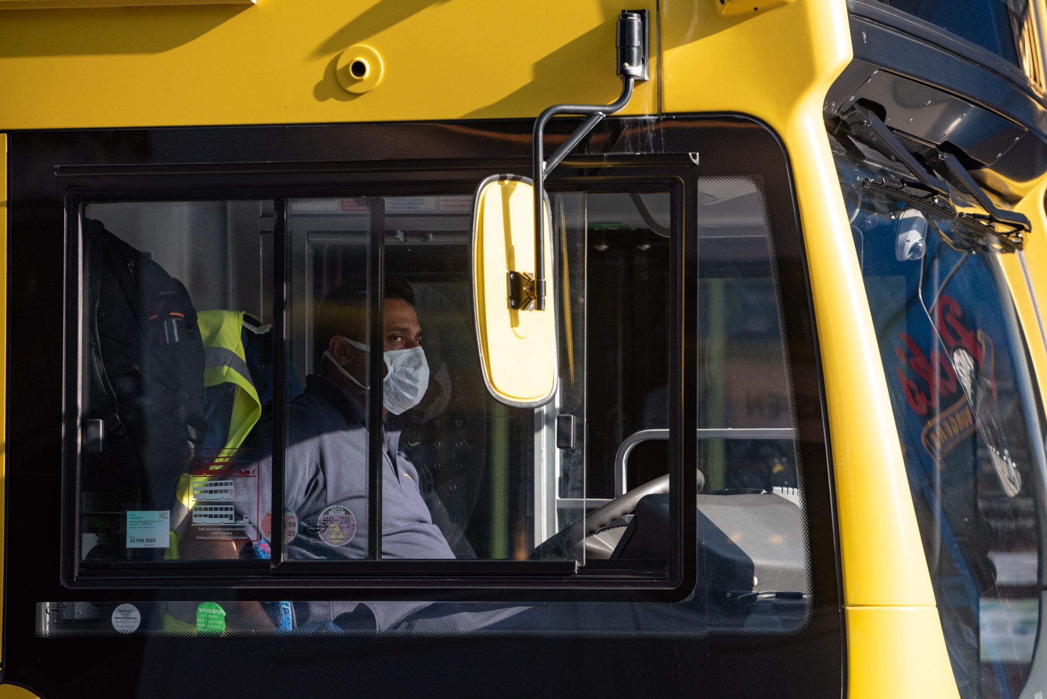 Man driving a Dublin Bus, wearing a mask