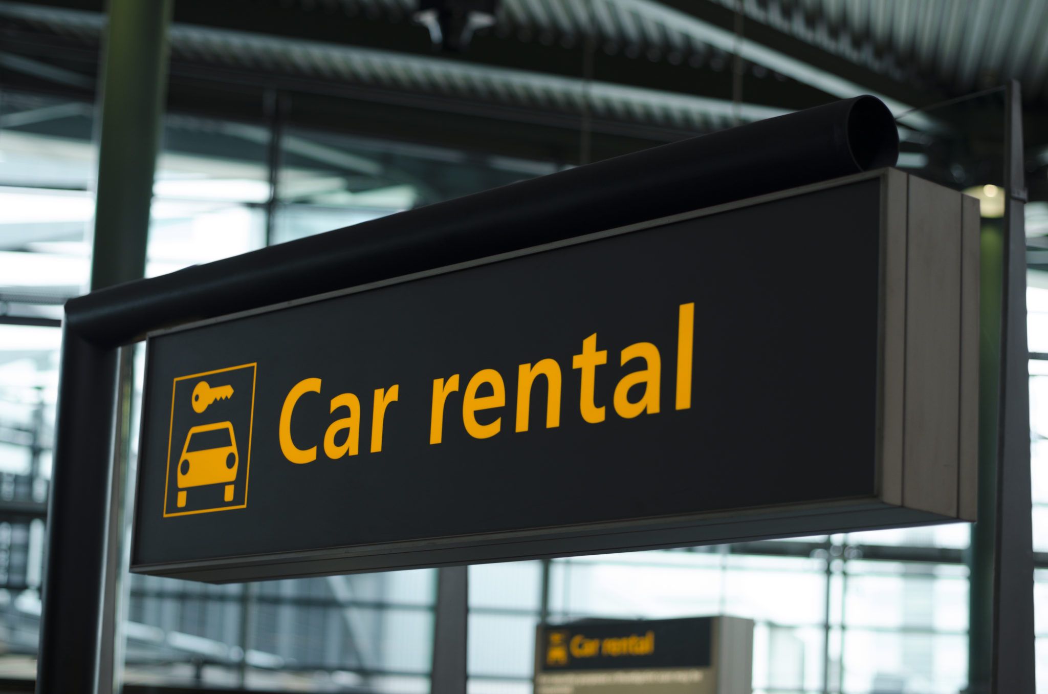 sign in an airport that reads "car rental" with an icon of a car and key
