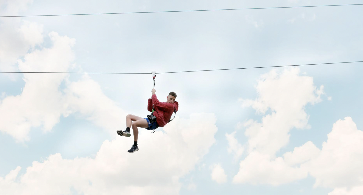 person zip lining with blue skies in the background
