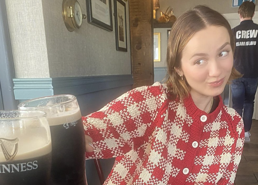 Maude Apatow sharing a 'cheers' over two pints of guinness with another person who is out of shot