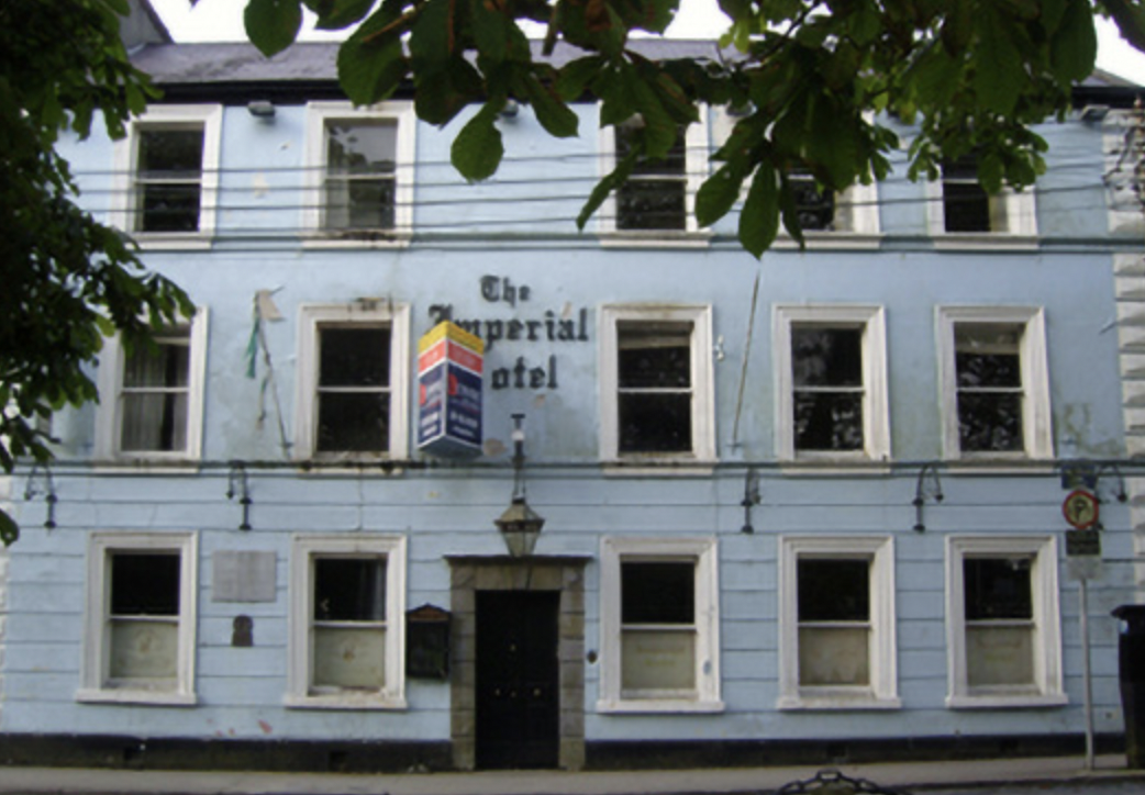 the imperial hotel in castlebar with a for sale sign above the door