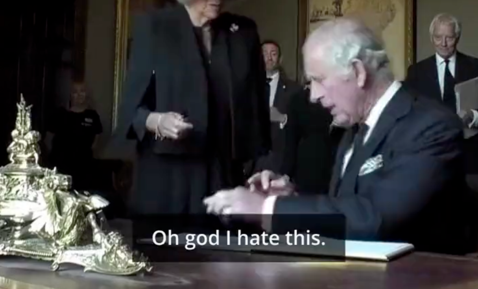 king charles signing a visitors book, caption reads 'oh god, I hate this'