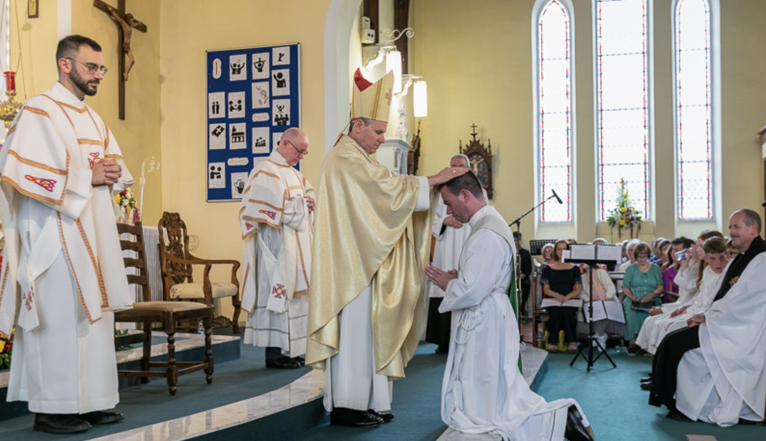 priest being ordained at a church, surrounded by other priests