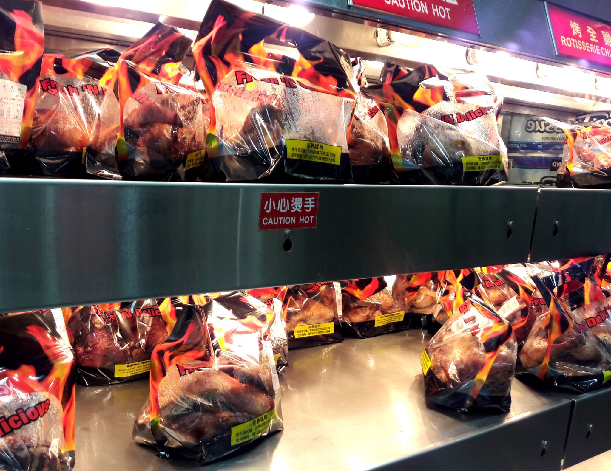 shelves of bagged rotisserie chickens in a supermarket