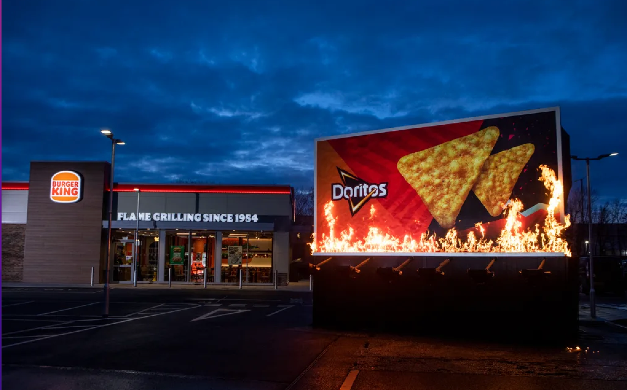 a billboard with an ad for Doritos in flames outside a burger king